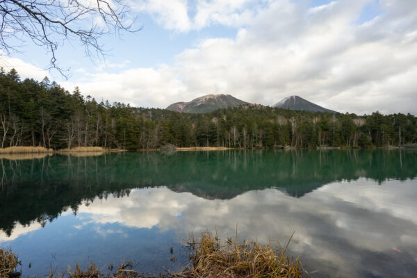 The still water of Lake Onneto reflects the peaks of Mt. Meakan and Akan Fuji in the late autumn near Ashoro, in Hokkaido, Japan.